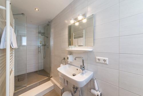 a white bathroom with a sink and a shower at Hotel Goldener Sternen in Konstanz