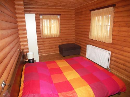 1 dormitorio con 1 cama colorida en una habitación de madera en Kedros Village, en Karpenisi