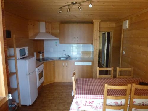 a small kitchen with a table and a white refrigerator at Joly Bois in Crest-Voland