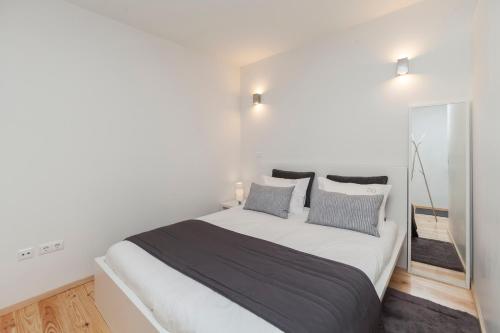 um quarto branco com uma cama grande e um espelho em BO - Almada no Porto