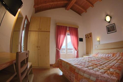 a bedroom with a bed and a table and a window at Liz Hotel & Apartments in Predazzo