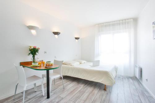 a bedroom with a bed and a table and chairs at Hôtel et Résidence Les Lauréades Clermont-Ferrand Centre Jaude in Clermont-Ferrand