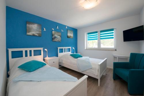 - une chambre avec 2 lits et un mur bleu dans l'établissement Ferienhaus Küstensegler, à Breege