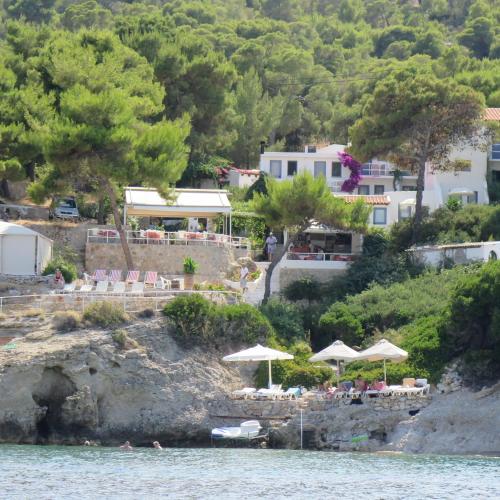 a beach with chairs and umbrellas on the water at Rosys Little Village in Skala