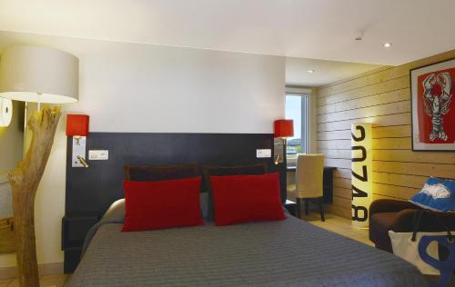 a bedroom with a bed with two red pillows at Logis Hôtel de la Pointe du Cap Coz in Fouesnant