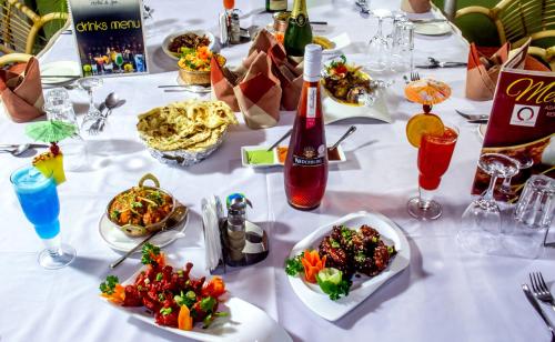 a table with plates of food and a bottle of soda at Fairway Boutique Hotel - Kampala, Uganda in Kampala