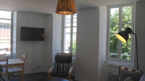 - un salon avec une table, une lampe et des fenêtres dans l'établissement Les Halles 1, à La Rochelle