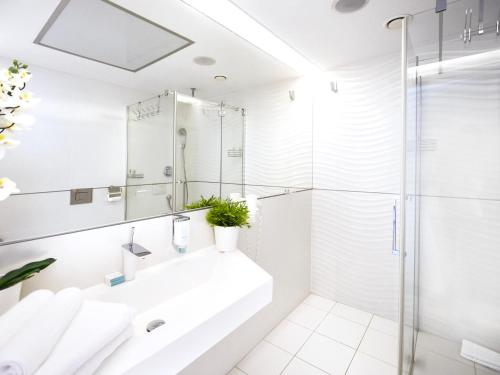 a white bathroom with a sink and a shower at VacationClub - Ultra Marine Apartment 36 in Kołobrzeg