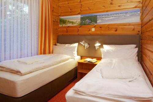 two beds in a room with wooden walls at Hotel Kaliebe in Trassenheide