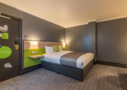 a bedroom with a bed with a green wall at Thistle Express London Luton in Luton