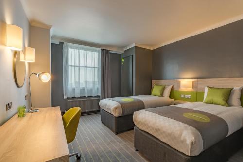 a hotel room with two beds and a desk at Thistle Express London Luton in Luton