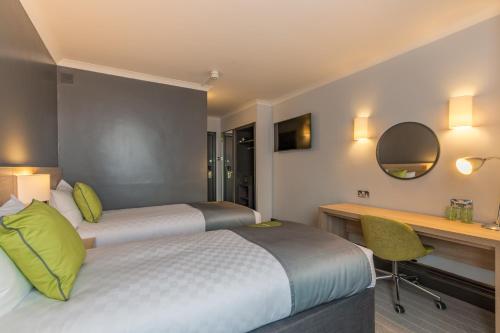 a hotel room with two beds and a desk at Thistle Express London Luton in Luton