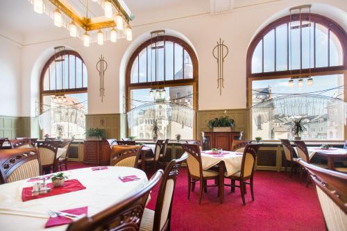 un restaurante con mesas, sillas y ventanas grandes en Hotel U Beránka Náchod en Náchod