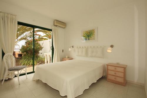 a white bedroom with a bed and a window at Casa Theresa in Los Barros