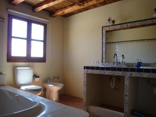 a bathroom with a tub and a toilet and a sink at Finca Can Pepis in Santa Agnès de Corona