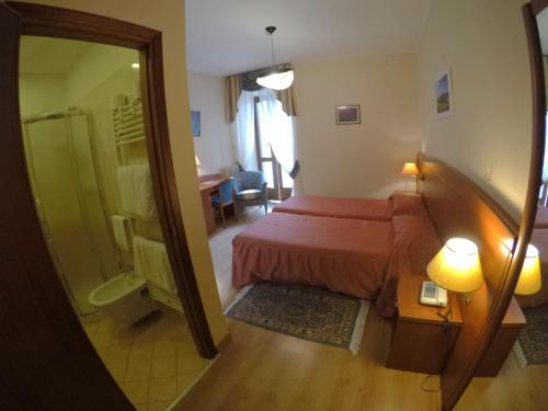 a bedroom with a bed and a shower and a mirror at Hotel Ristorante Combolo in Teglio