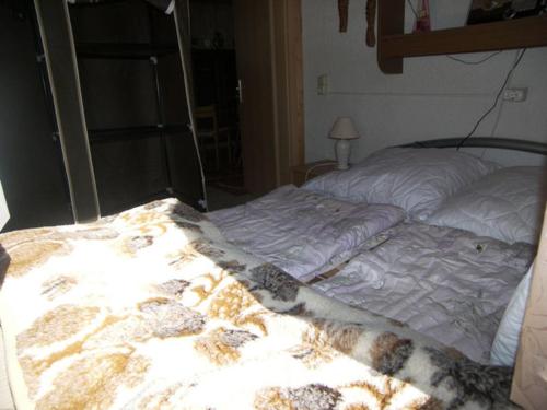 Una cama sin hacer en un dormitorio con una manta. en Bungalow am Schmollensee, en Sellin