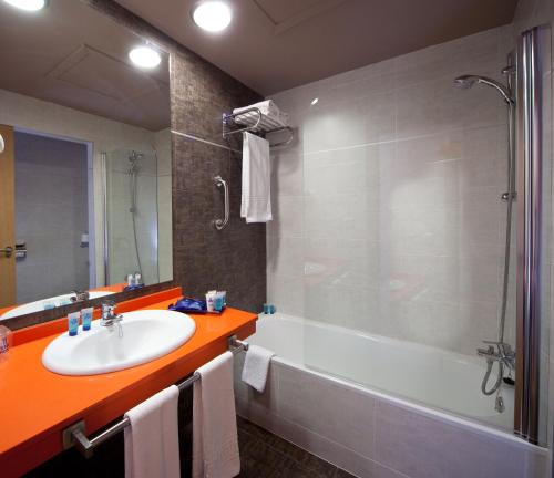 La salle de bains est pourvue d'une baignoire, d'un lavabo et d'une douche. dans l'établissement Evenia Zoraida Garden, à Roquetas de Mar
