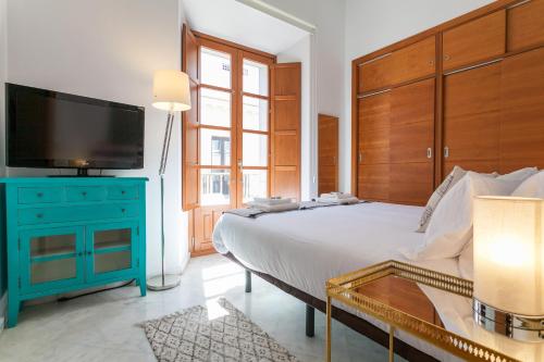een slaapkamer met een groot bed, een blauwe dressoir en een televisie bij Luxury Rooftop - Space Maison Apartments in Sevilla