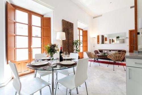 a dining room with a glass table and white chairs at Luxury Rooftop - Space Maison Apartments in Seville