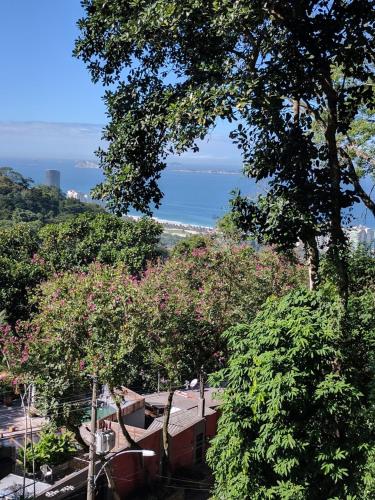 a view of the ocean from behind some trees at Casa Verde Río in Rio de Janeiro