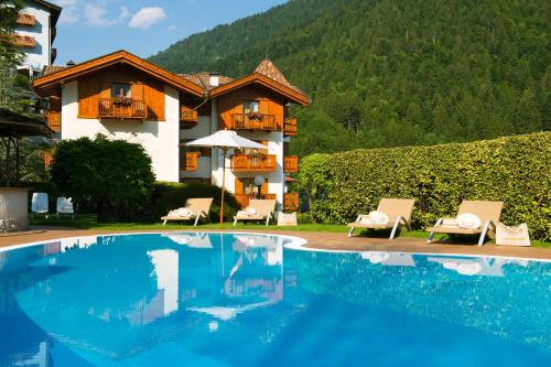 a resort with a swimming pool and a house at Hotel Du Lac in Molveno