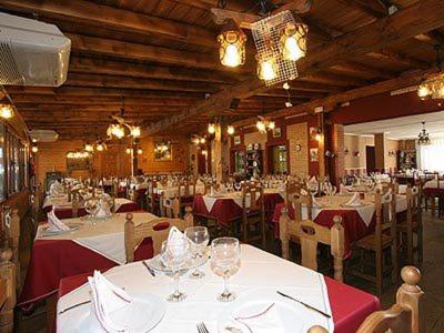 Hosteria San Emeterio في إيسلا: غرفة طعام مع طاولات بيضاء وكراسي مع قماش الطاولة الحمراء