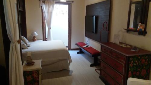 a bedroom with a bed and a dresser and a television at Be Hospedagem in Lumiar