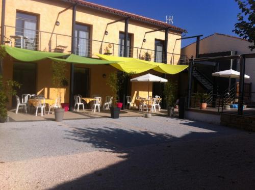 a patio with tables and umbrellas in front of a building at La Petite Ecole in Marciac