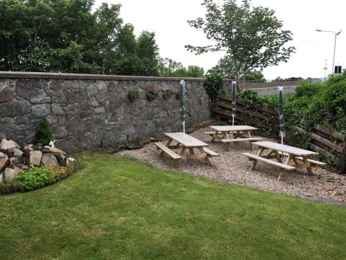 two picnic tables in front of a stone wall at Belgrave Arms Hotel in Helmsdale