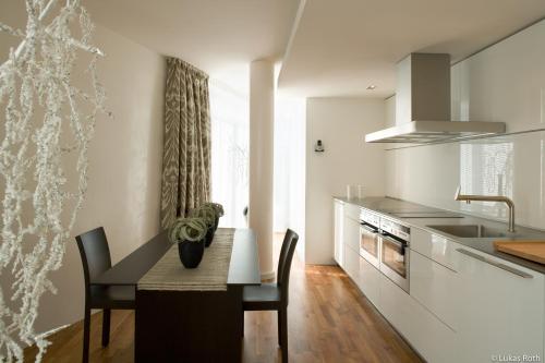 a kitchen with a table and chairs and a kitchen with a sink at The Mandala Berlin, a Member of Design Hotels in Berlin