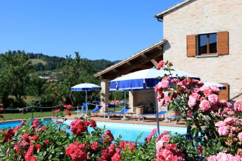 a house and a swimming pool with flowers at Parco Ducale Country House in Urbania