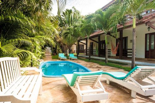 a swimming pool with two chairs and a house at Recanto do Barao Pousada in Jericoacoara