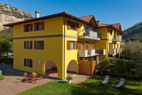 a yellow building with a yard with chairs at Casa Carla in Nago-Torbole