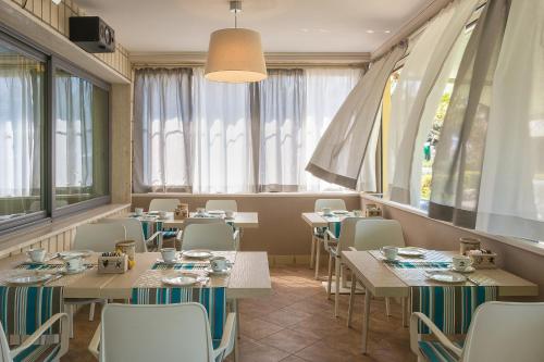 a restaurant with tables and chairs and windows at Hotel Siesta in Lido di Camaiore