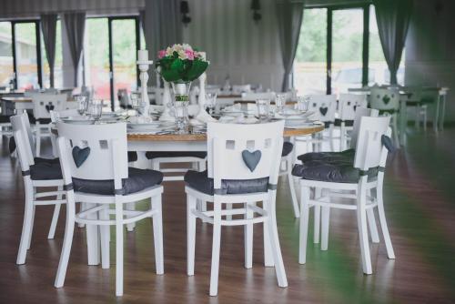 a dining room with a table with white chairs at Hotel Turkovia in Turek