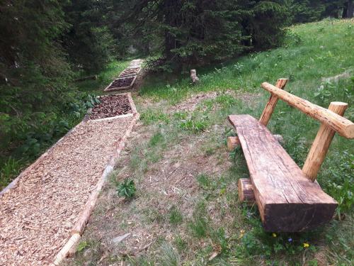 a wooden bench sitting in the grass next to a garden at Apartma David Rogla in Zreče