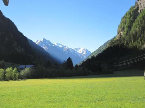 a large green field with mountains in the background at Apart Alpenflair in Sankt Leonhard im Pitztal