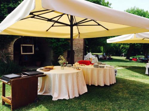 two tables under a large umbrella in the grass at Agriturismo La Lupa in Madonna della Provvidenza