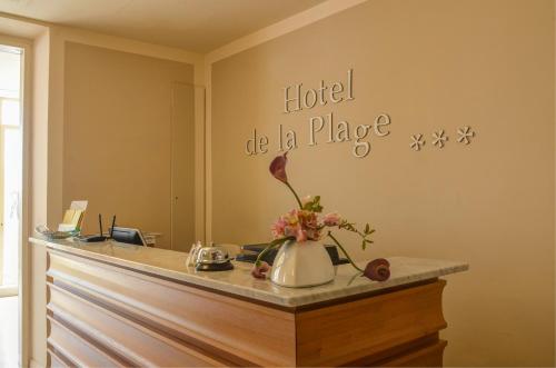 a hotel be a place sign on a counter with flowers at Hotel De La Plage in Pietra Ligure