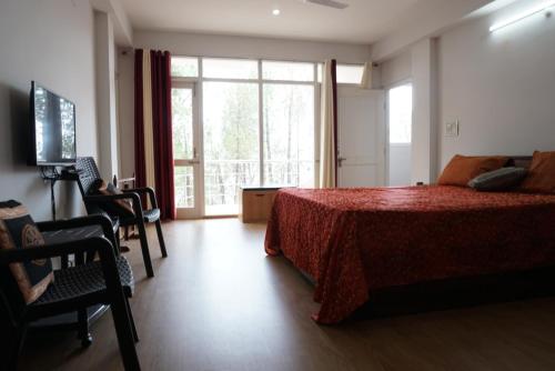 Un dormitorio con una cama y una ventana grande. en Satobari Greens Homestay, en McLeod Ganj