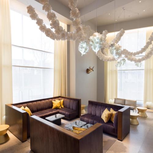a living room with a couch and a chandelier at 21c Museum Hotel Durham in Durham