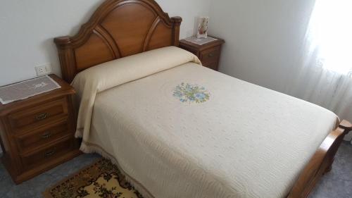 a bed with a wooden headboard and a night stand at Casa de Forno in Queijadoiro
