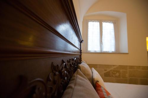 a bedroom with a wooden headboard and a window at Giardini 82 B&B in Gravina in Puglia