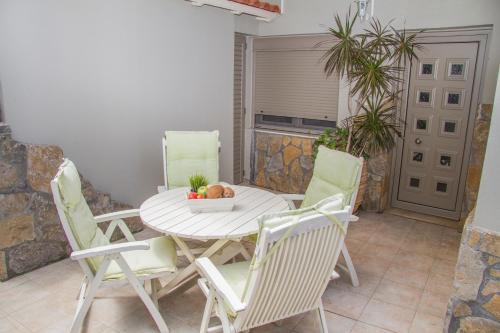 a white table and chairs with a bowl of fruit on it at Attalos Apartments in Agia Pelagia