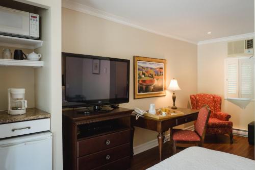 Habitación de hotel con TV y escritorio con silla. en Green Acres Inn en Kingston