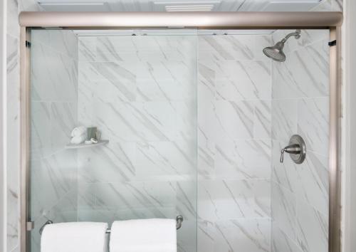 uma casa de banho com um chuveiro e azulejos de mármore branco em Shem Creek Inn em Charleston