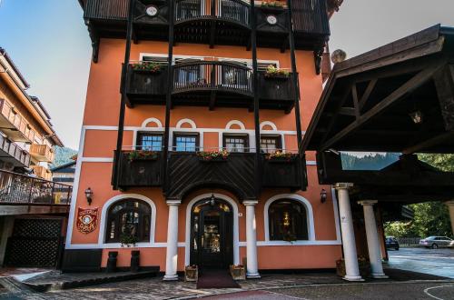 a tall orange building with a balcony at Hotel Posta R.T.A. in Madonna di Campiglio