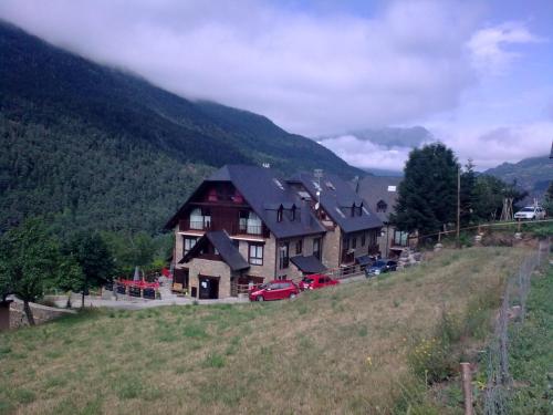 a large house on a hill with cars parked in a field at Hotelet de Betlan in Betlán
