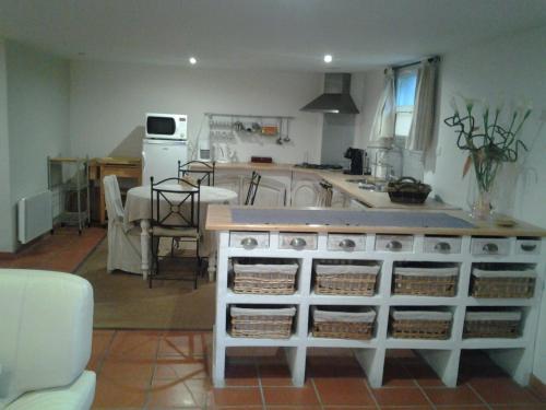 a kitchen with a counter and a table with baskets at Les Chambres d'Hôtes de la Ferrage in La Tour-dʼAigues